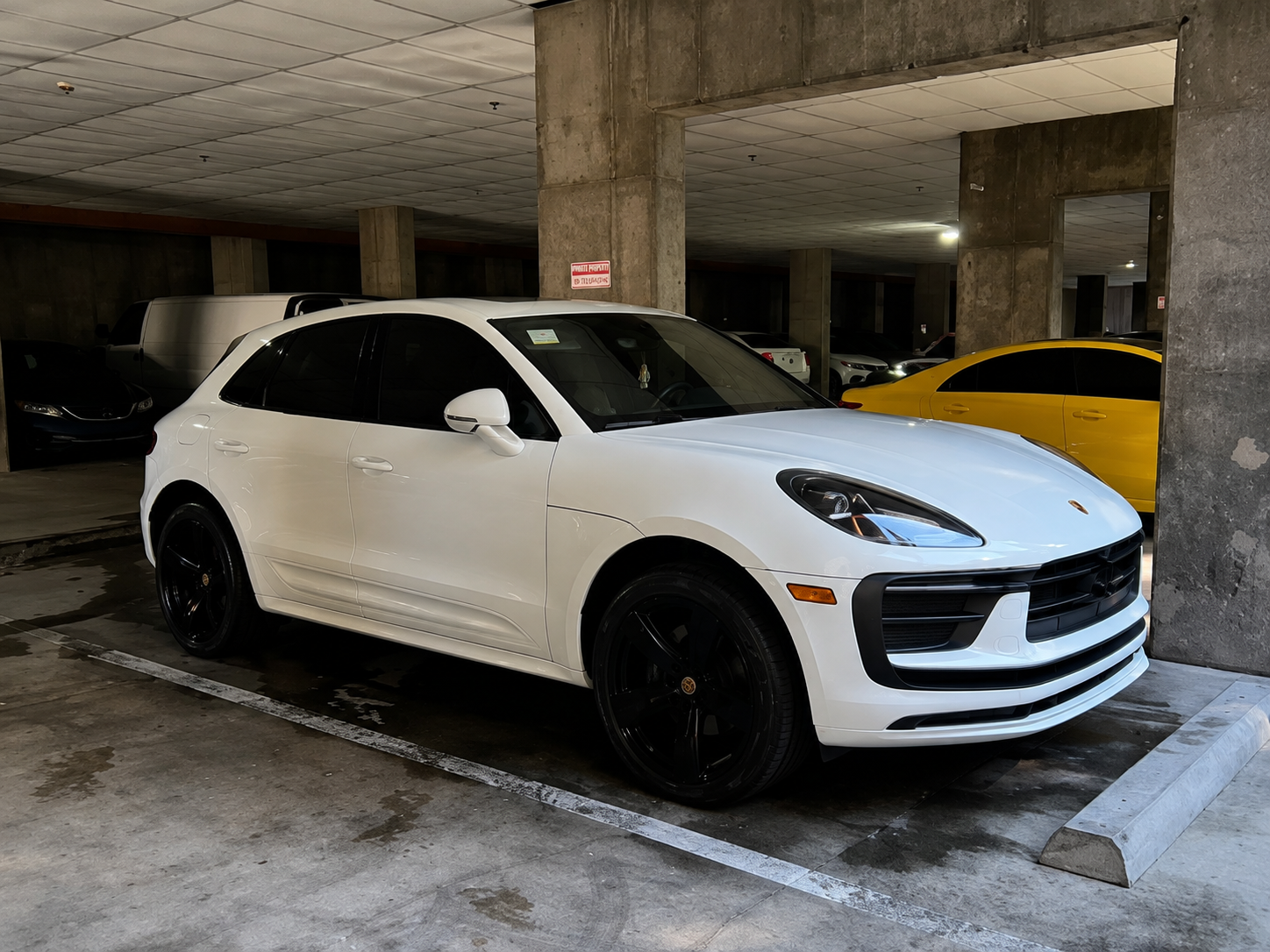 White Porsche Macan detailed to a mirror shine in a parking garage